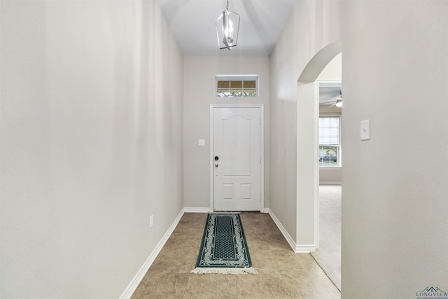 doorway to outside featuring arched walkways, carpet flooring, and baseboards