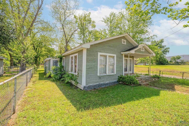 view of home's exterior with a storage unit, fence, an outdoor structure, and a lawn