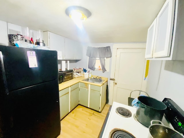kitchen with a sink, light wood-style floors, light countertops, and freestanding refrigerator