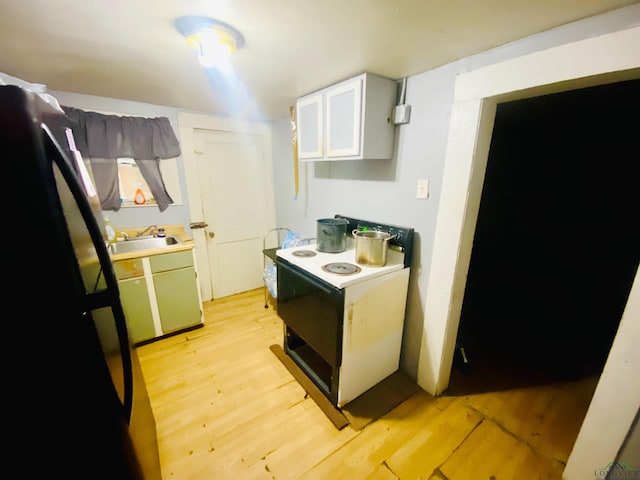 kitchen with electric stove, light countertops, light wood-style flooring, and a sink