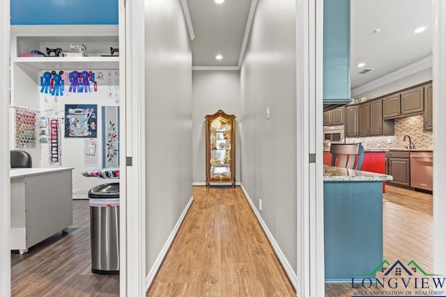 hallway featuring wood-type flooring, ornamental molding, and sink