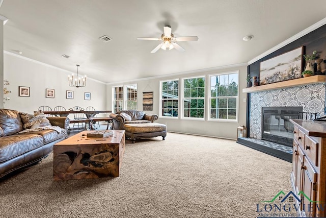 living room with a fireplace, ornamental molding, carpet flooring, and ceiling fan with notable chandelier