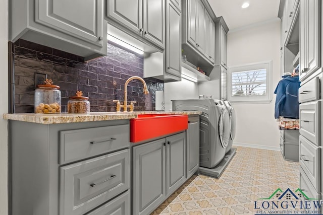 laundry room featuring ornamental molding, sink, washer and clothes dryer, and cabinets