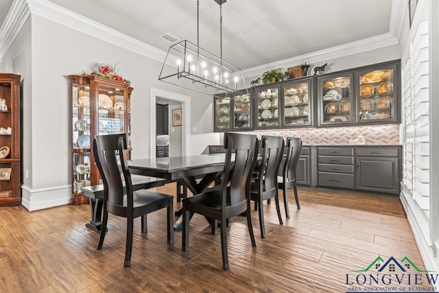 dining space featuring crown molding, wood-type flooring, and an inviting chandelier