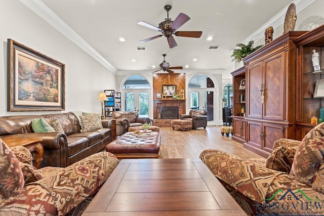 living room with a fireplace, ornamental molding, light wood-type flooring, and ceiling fan