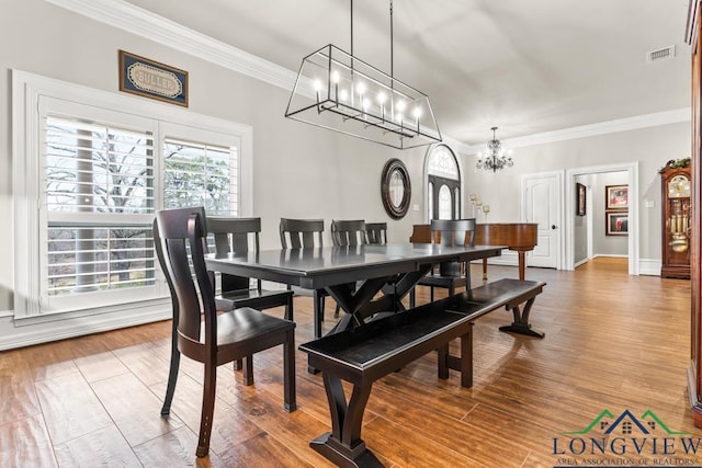 dining room featuring hardwood / wood-style flooring, crown molding, and a chandelier