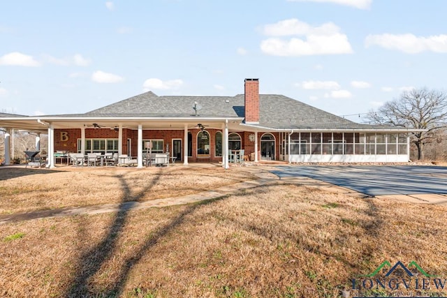 back of property with a yard, a patio, a sunroom, and ceiling fan