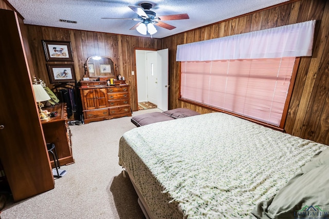 carpeted bedroom featuring a textured ceiling, ceiling fan, and wood walls