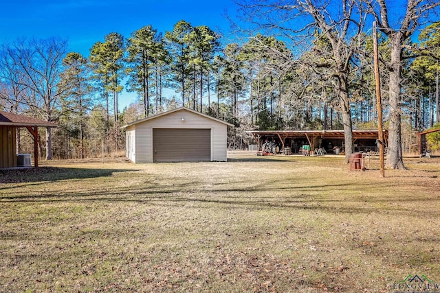 view of yard featuring a garage, an outbuilding, and central air condition unit