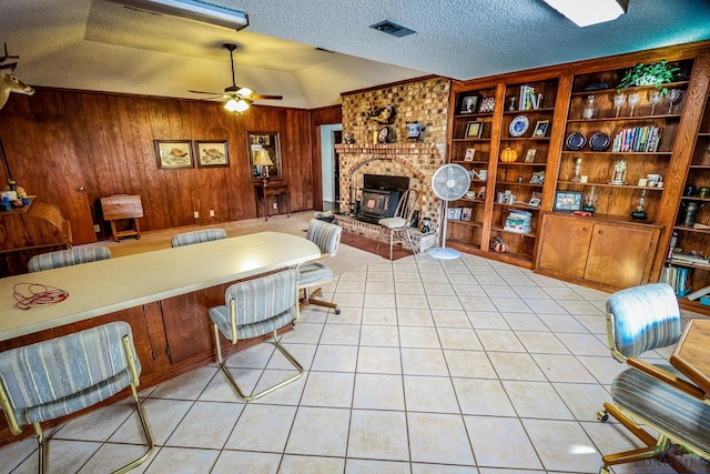 living room with wood walls, a raised ceiling, ceiling fan, light tile patterned floors, and a textured ceiling