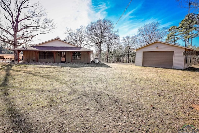 view of yard featuring a porch, a garage, and an outdoor structure