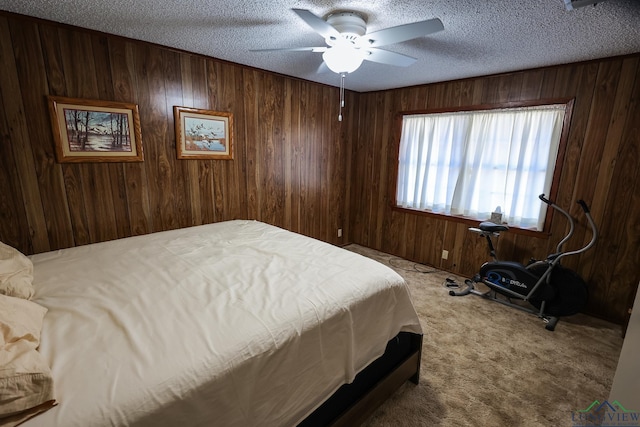 bedroom with a textured ceiling, carpet floors, ceiling fan, and wood walls