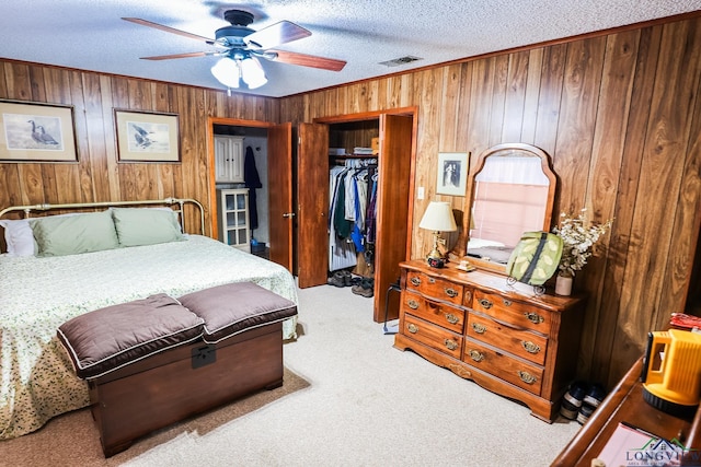 bedroom featuring ceiling fan, light colored carpet, a textured ceiling, wooden walls, and a closet