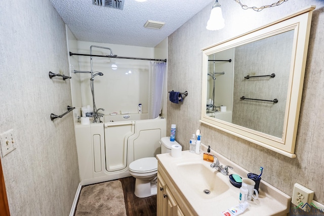 full bathroom featuring vanity, hardwood / wood-style flooring, toilet, a textured ceiling, and shower / tub combo with curtain