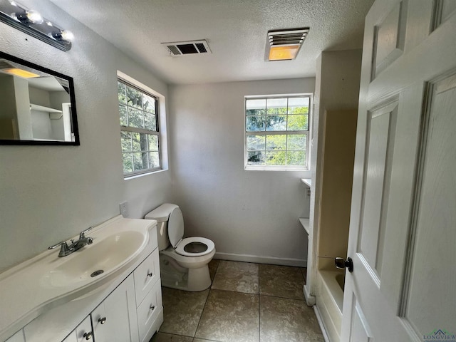 bathroom featuring a textured ceiling, vanity, tile patterned flooring, toilet, and a tub