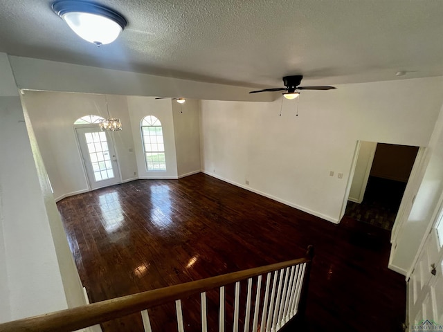 interior space featuring dark wood-type flooring and ceiling fan with notable chandelier