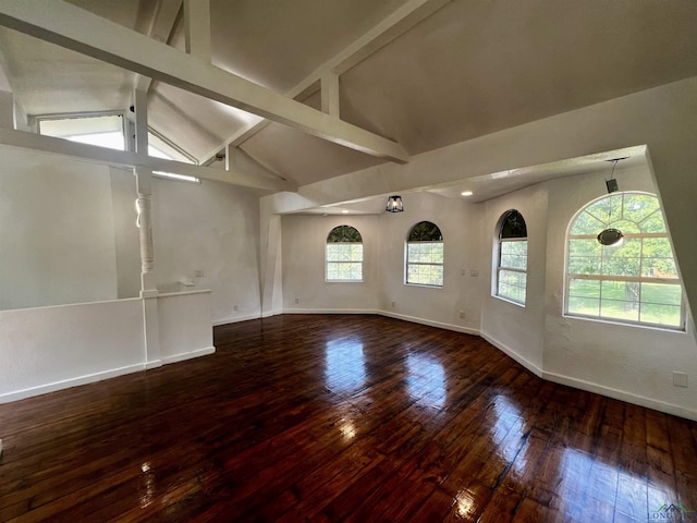 spare room featuring hardwood / wood-style floors, lofted ceiling with beams, and a healthy amount of sunlight