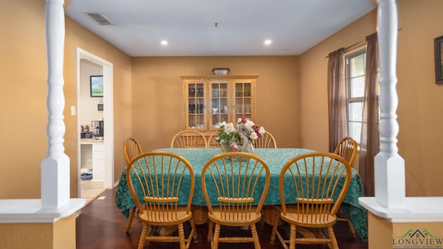 dining area featuring decorative columns and wood-type flooring