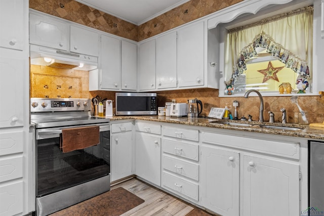 kitchen with appliances with stainless steel finishes, backsplash, sink, dark stone countertops, and white cabinets