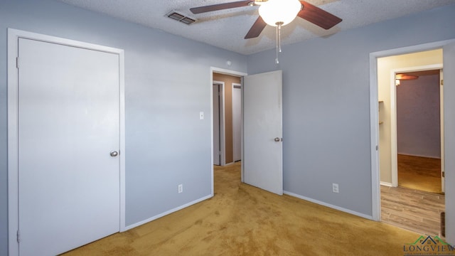 unfurnished bedroom featuring a textured ceiling, light colored carpet, and ceiling fan