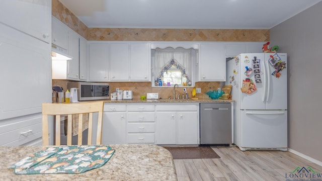 kitchen with white cabinets, sink, stainless steel appliances, and light hardwood / wood-style flooring