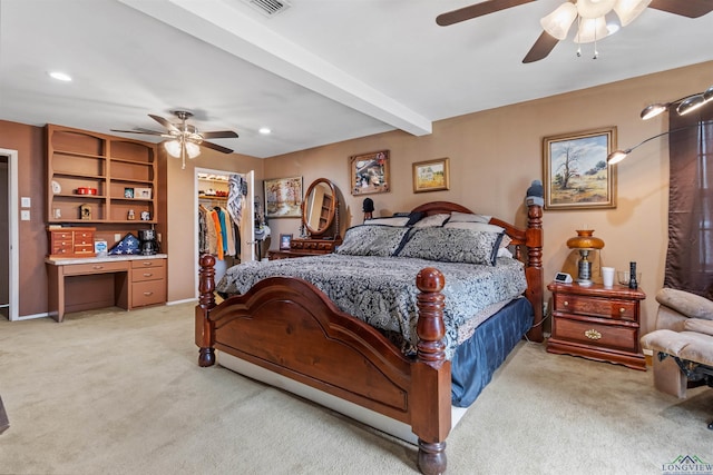 carpeted bedroom featuring beam ceiling, a walk in closet, ceiling fan, and a closet