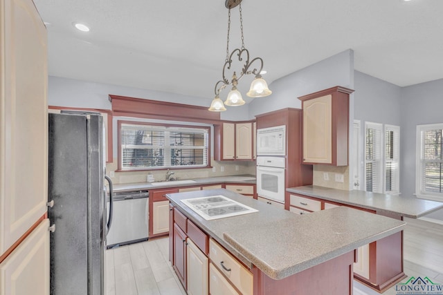 kitchen with white appliances, light wood finished floors, a kitchen island, light countertops, and a sink