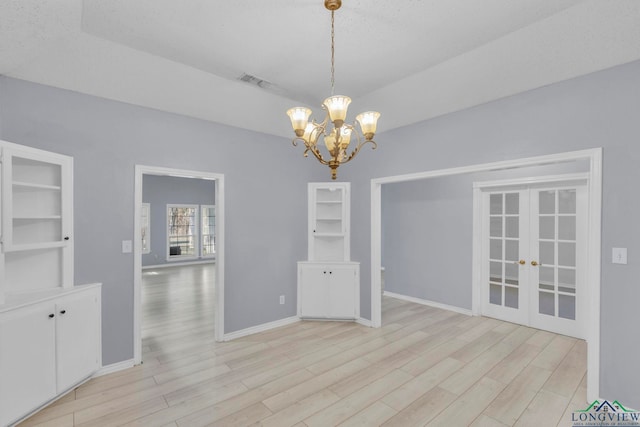 unfurnished dining area featuring light wood finished floors, french doors, a chandelier, and baseboards