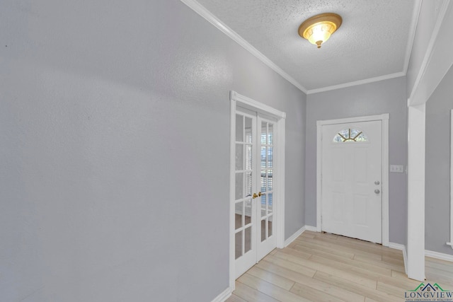 foyer featuring crown molding, a textured ceiling, baseboards, and wood finished floors