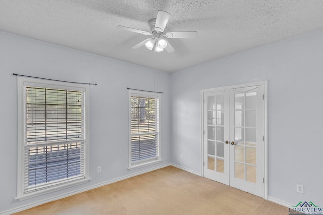 carpeted empty room featuring a textured ceiling, french doors, and a ceiling fan