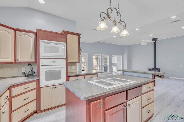 kitchen with tasteful backsplash, light countertops, visible vents, a wood stove, and white appliances