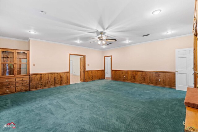 825 University Dr, Carthage, TX 75633 - unfurnished room with a wainscoted wall, a ceiling fan, wooden walls, ornamental molding, and carpet