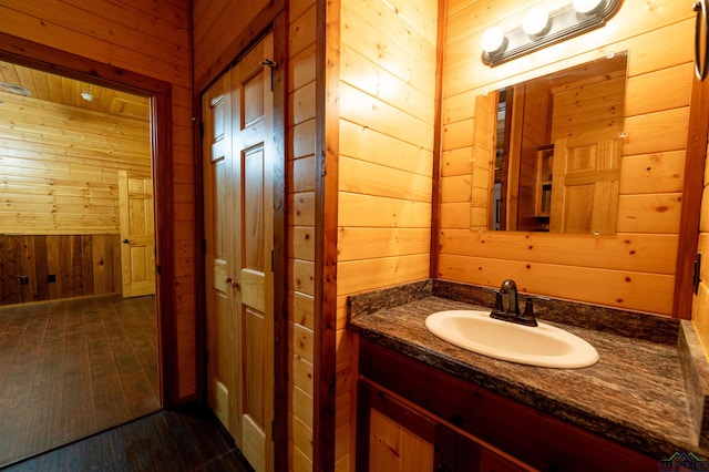 bathroom with vanity, wood-type flooring, and wood walls