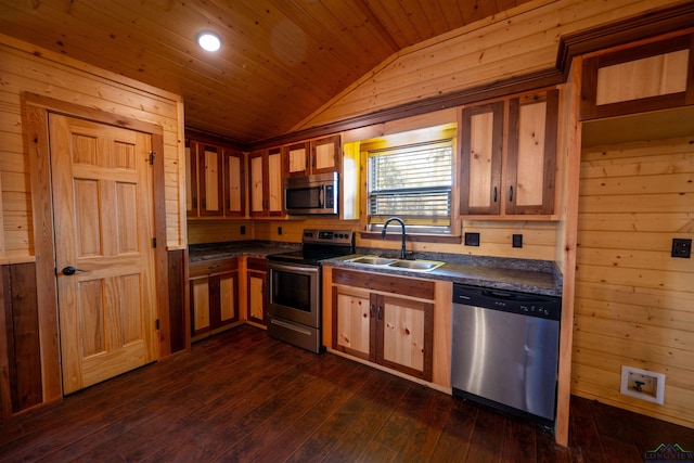 kitchen with sink, dark wood-type flooring, appliances with stainless steel finishes, vaulted ceiling, and wood walls