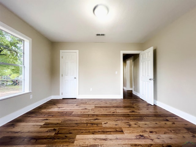 unfurnished bedroom featuring dark wood-type flooring and multiple windows