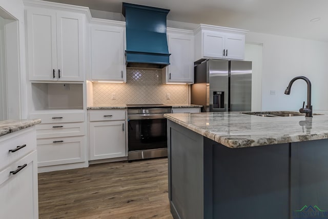 kitchen featuring premium range hood, sink, white cabinetry, light stone counters, and appliances with stainless steel finishes