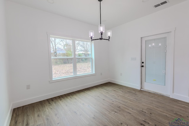 unfurnished dining area with an inviting chandelier and hardwood / wood-style floors