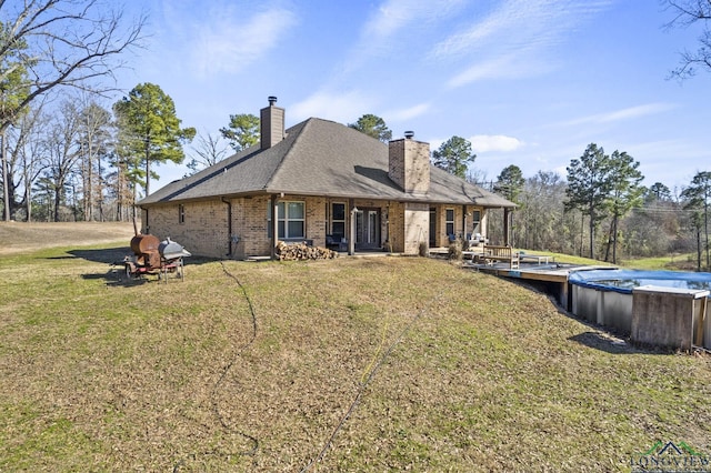 rear view of house featuring a yard and a covered pool