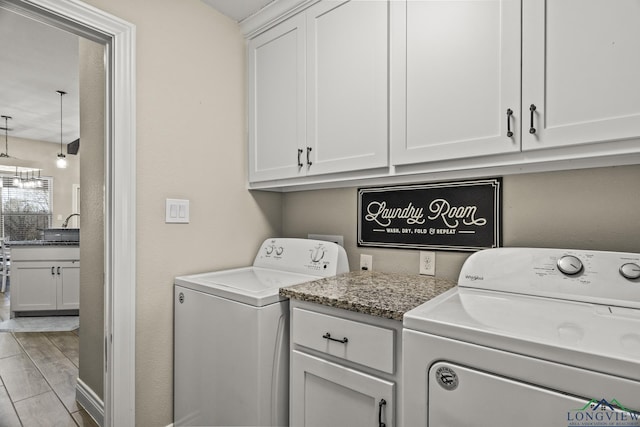 clothes washing area with cabinets, washer and dryer, and sink