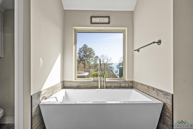 bathroom featuring a tub, tile walls, and toilet