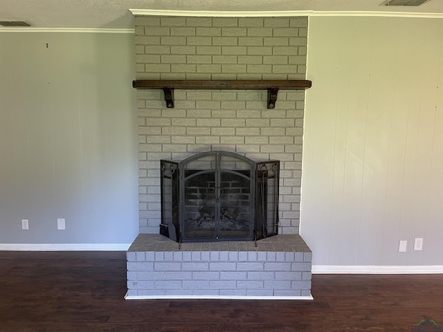 interior details featuring a textured ceiling, a brick fireplace, wood finished floors, and crown molding