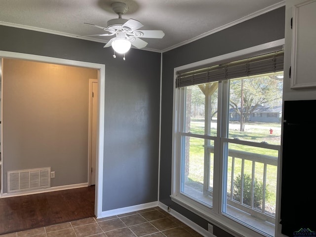 interior space featuring visible vents, plenty of natural light, dark tile patterned flooring, and ornamental molding