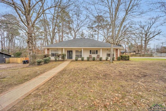 single story home featuring a porch, brick siding, fence, and a front lawn