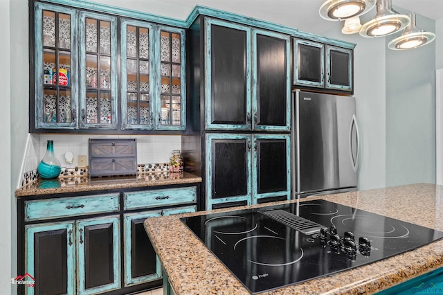 1463 County Road 106, Carthage, TX 75633 - kitchen featuring freestanding refrigerator, black electric cooktop, glass insert cabinets, tasteful backsplash, and light stone countertops