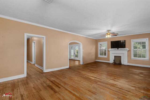 1204 Collins St, Henderson, TX 75654 - unfurnished living room with arched walkways, wood finished floors, plenty of natural light, crown molding, and baseboards