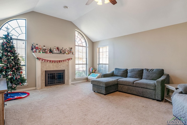 living room featuring a tile fireplace, light colored carpet, vaulted ceiling, and ceiling fan