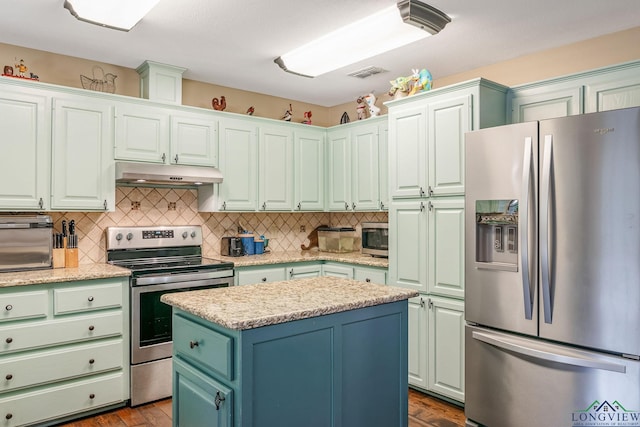 kitchen featuring a center island, tasteful backsplash, light stone counters, wood-type flooring, and appliances with stainless steel finishes