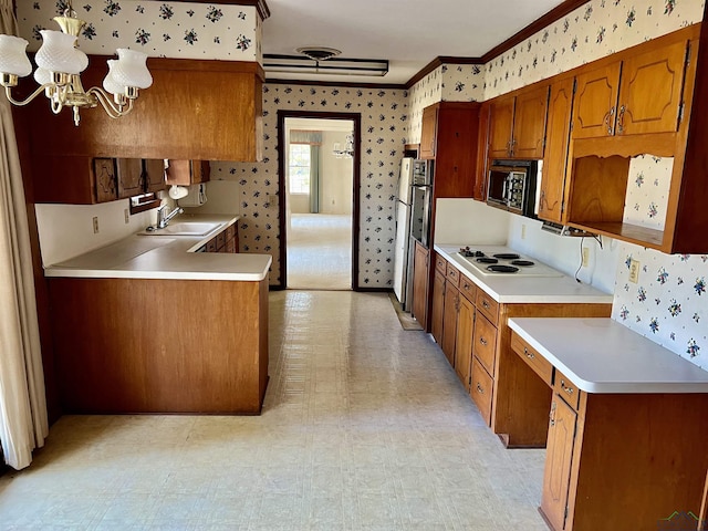 kitchen with sink, crown molding, appliances with stainless steel finishes, a notable chandelier, and kitchen peninsula