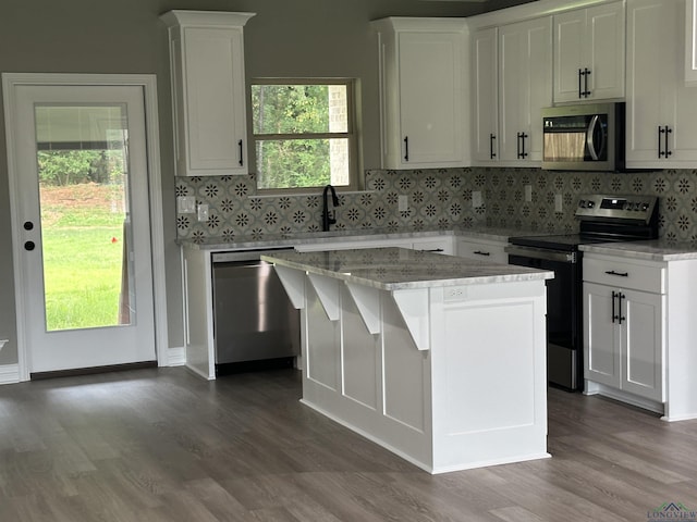 kitchen featuring hardwood / wood-style floors, a center island, white cabinetry, and appliances with stainless steel finishes