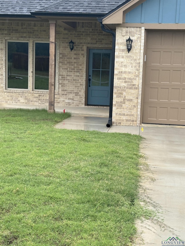 property entrance with a garage and a lawn